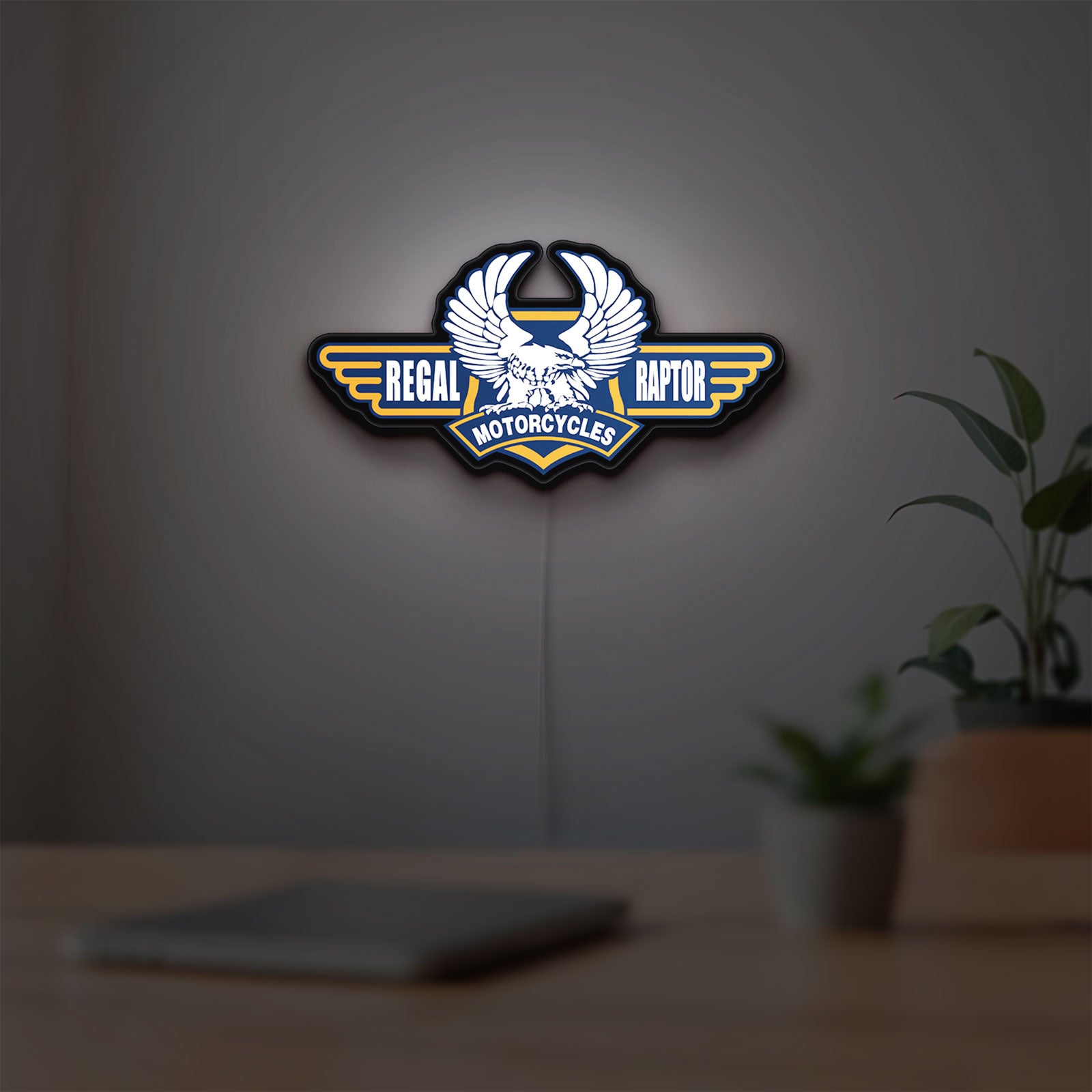 Regal Raptor Motorcycles LED lightbox hanging on a room wall with soft orange light