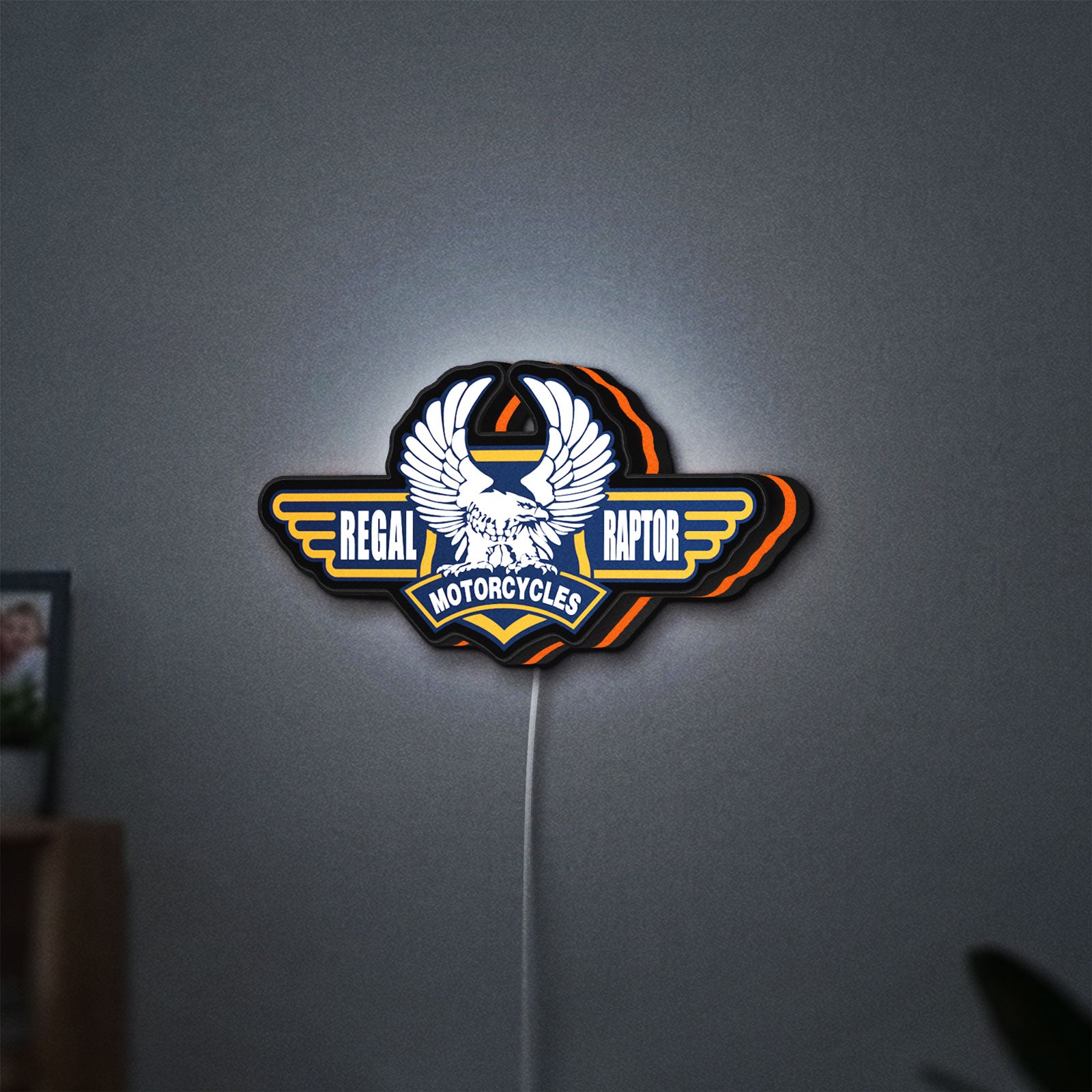 Regal Raptor Motorcycles LED lightbox hanging on a wall with orange glow