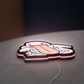 Lickitung LED lightbox lying flat on a desk with pink glow