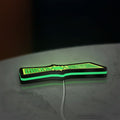 Green Lantern LED lightbox lying flat on a desk with green glow