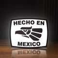 Front view of Hecho en Mexico LED lightbox sign glowing on a wooden desk