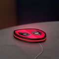 Deadpool Head LED lightbox lying flat on a desk with red glow