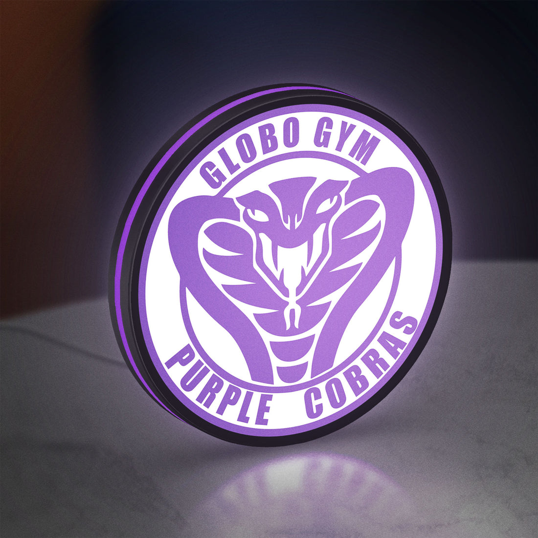 Dodgeball Globo Gym Purple Cobras LED lightbox hanging on a wall with purple glow