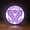 Front view of Dodgeball Globo Gym Purple Cobras LED lightbox sign glowing on a wooden desk