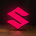 Front view of Suzuki LED lightbox sign glowing on a wooden desk