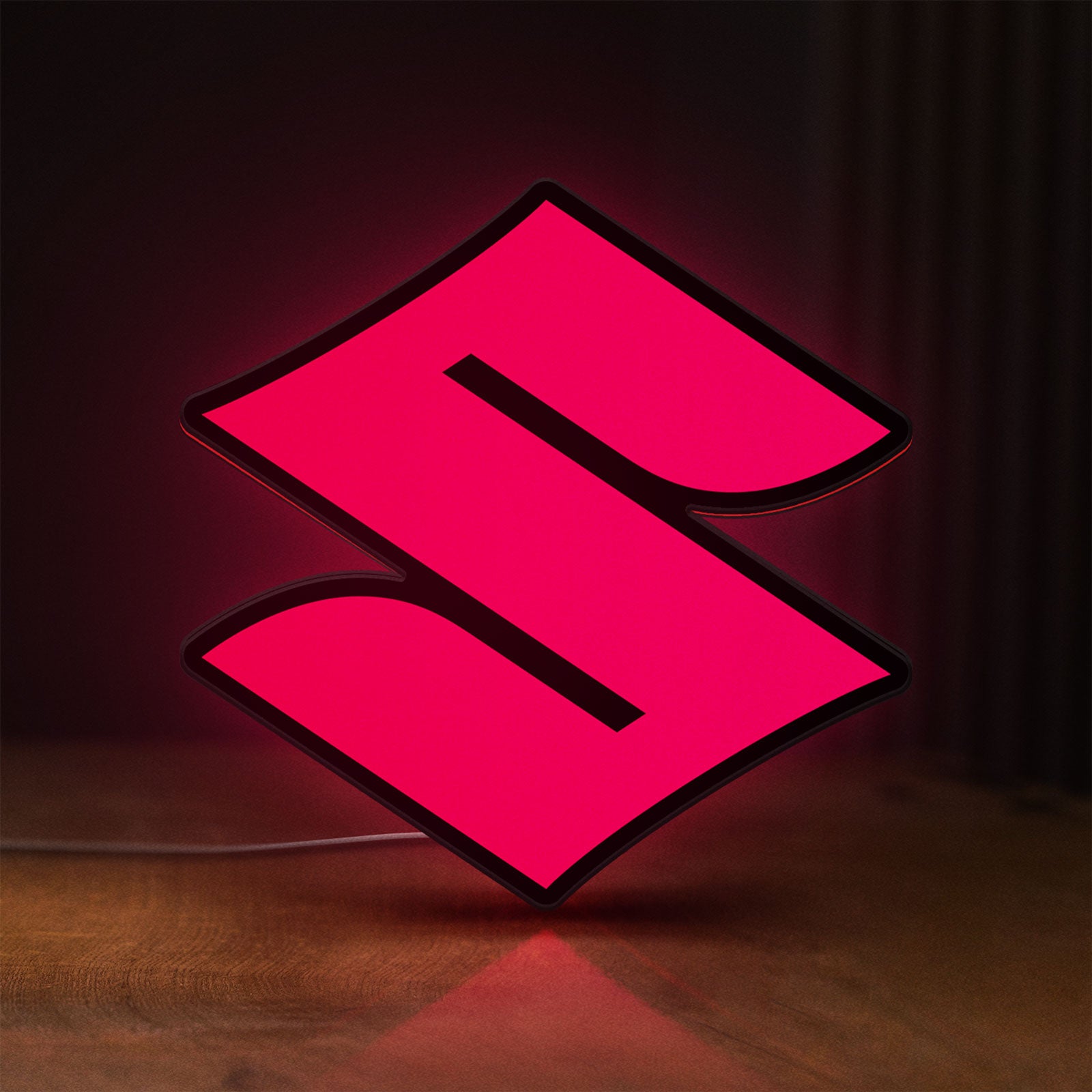 Front view of Suzuki LED lightbox sign glowing on a wooden desk
