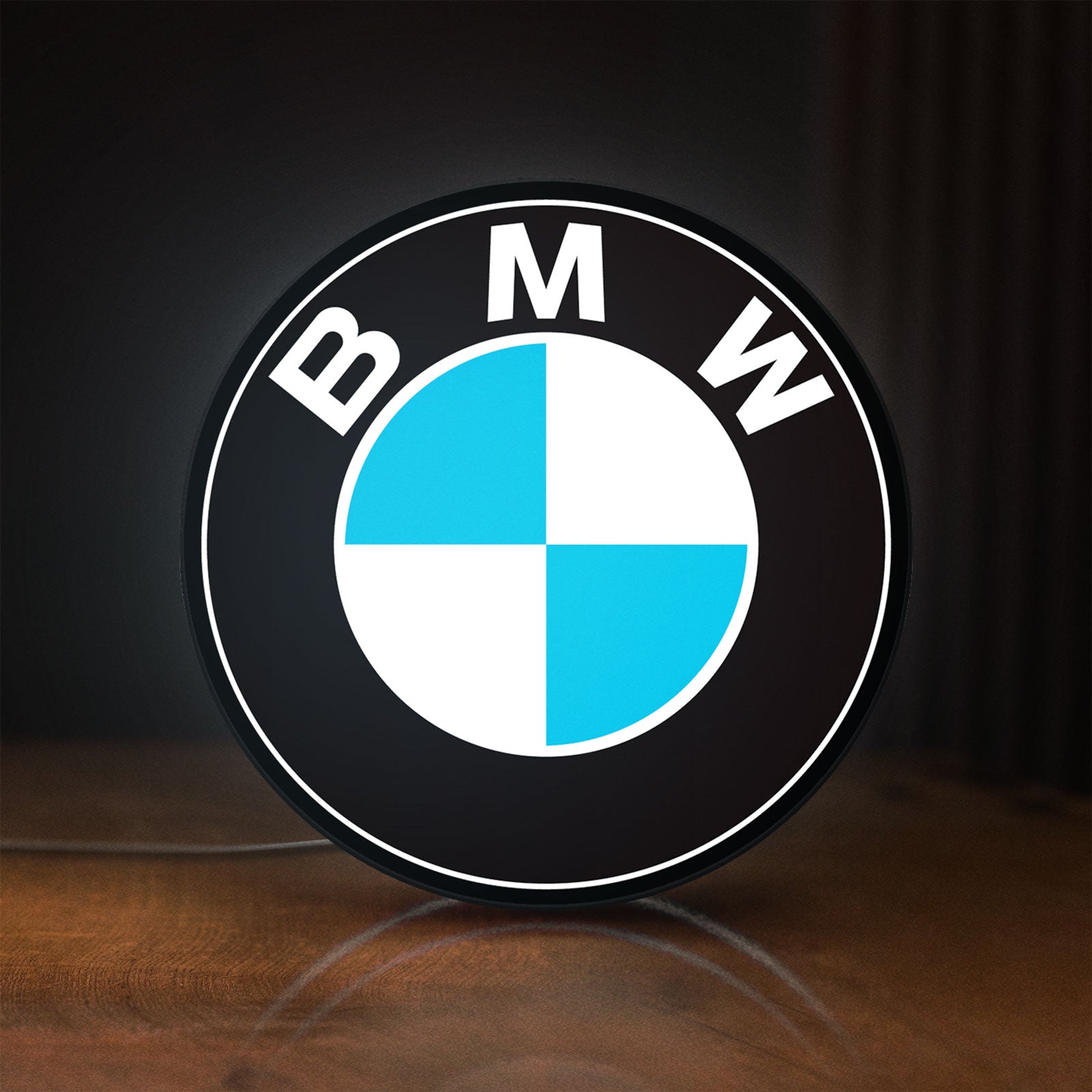 Front view of BMW LED lightbox sign glowing on a wooden desk