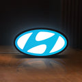 Front view of Hyundai LED lightbox sign glowing on a wooden desk