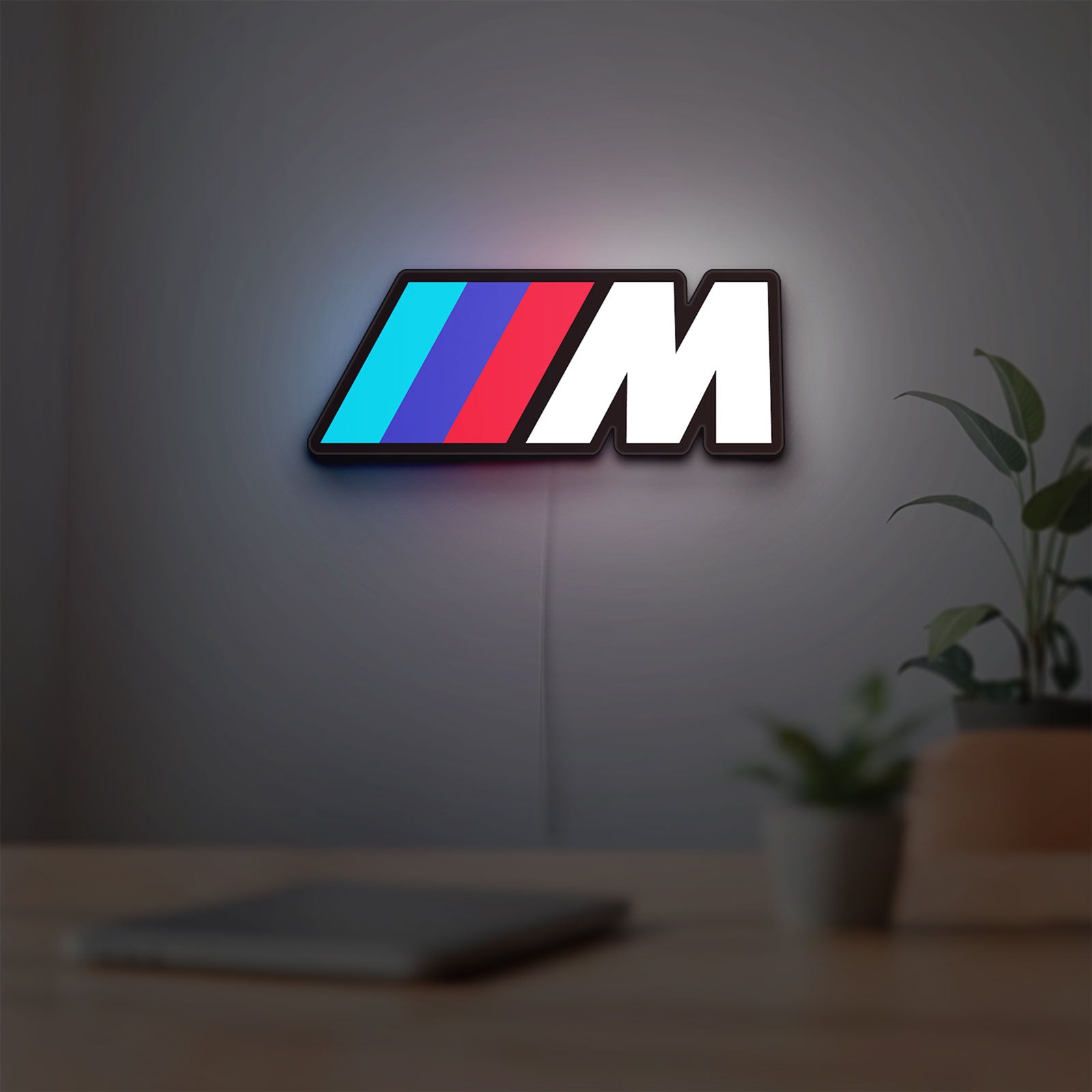 BMW M LED lightbox hanging on a room wall with soft white light