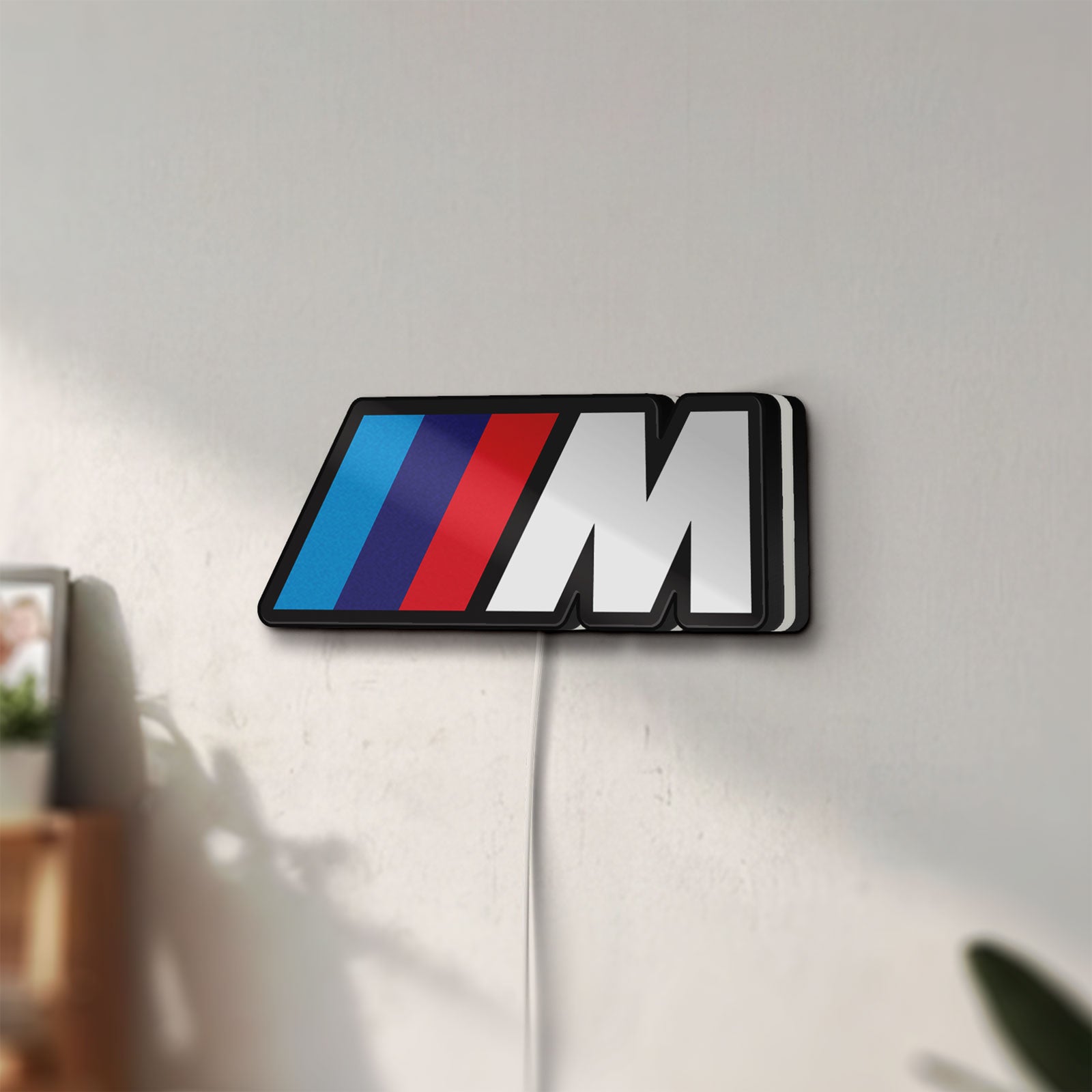 Unlit BMW M LED lightbox mounted on a wall in daylight