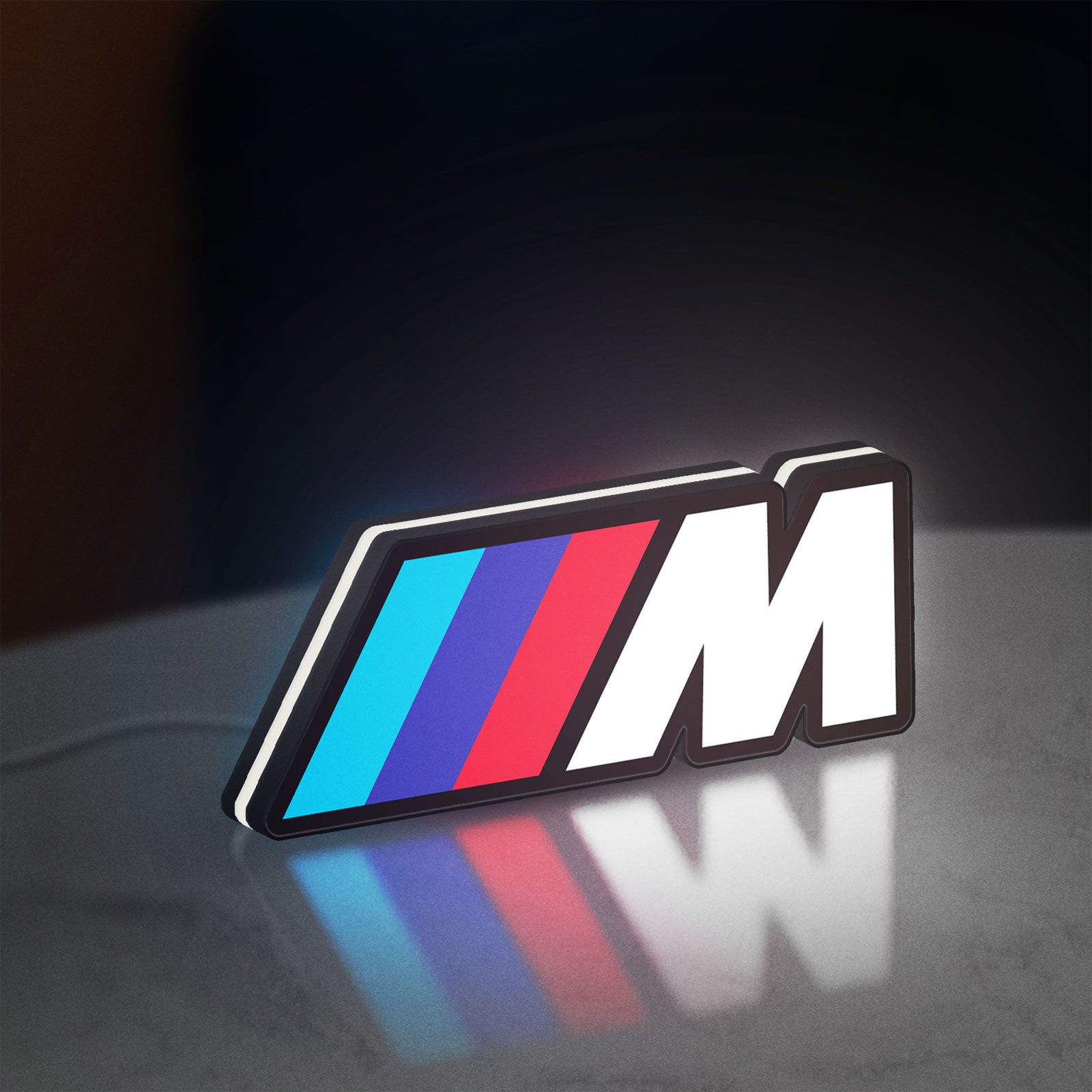 BMW M LED lightbox standing on a desk from an angled side view with white glow