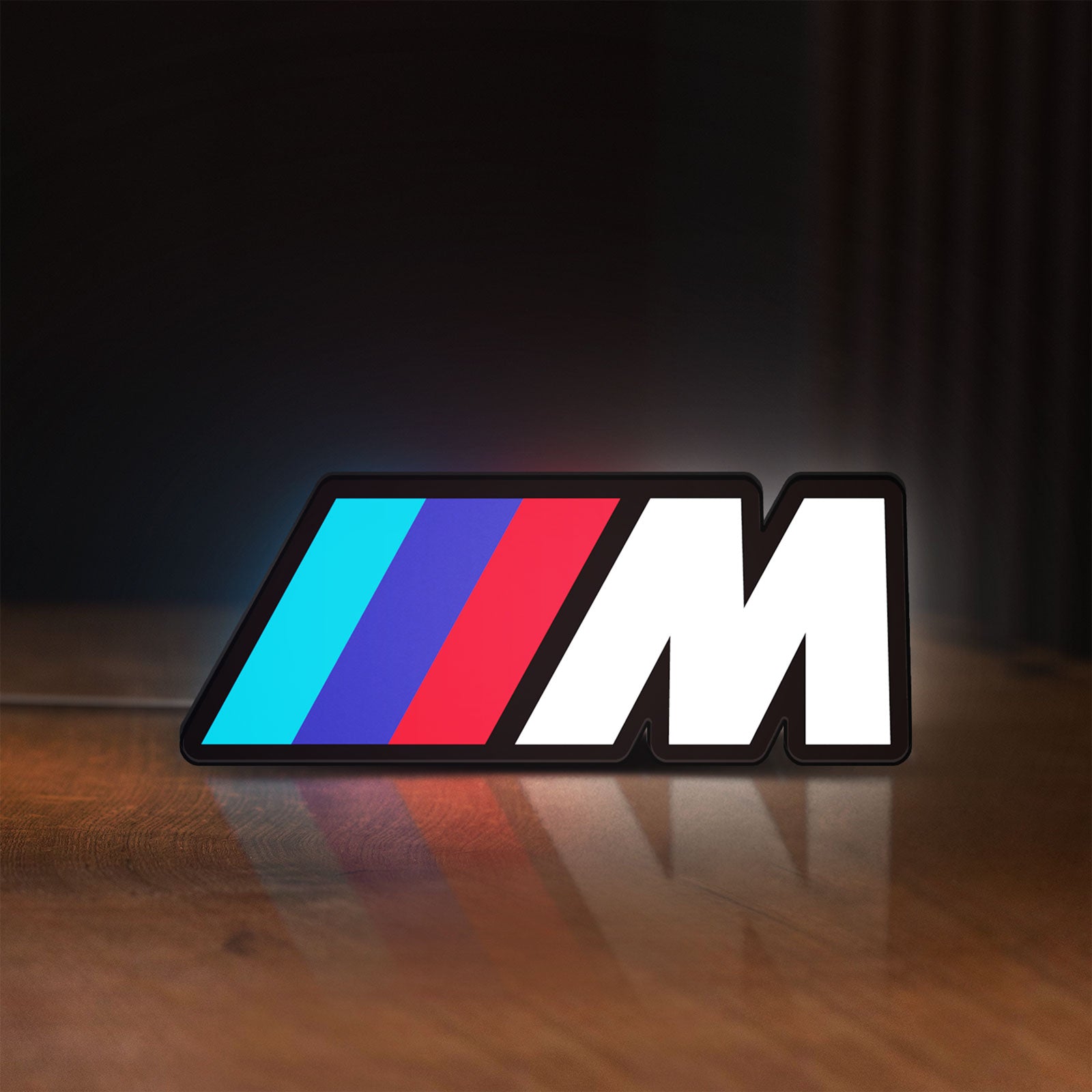 Front view of BMW M LED lightbox sign glowing on a wooden desk