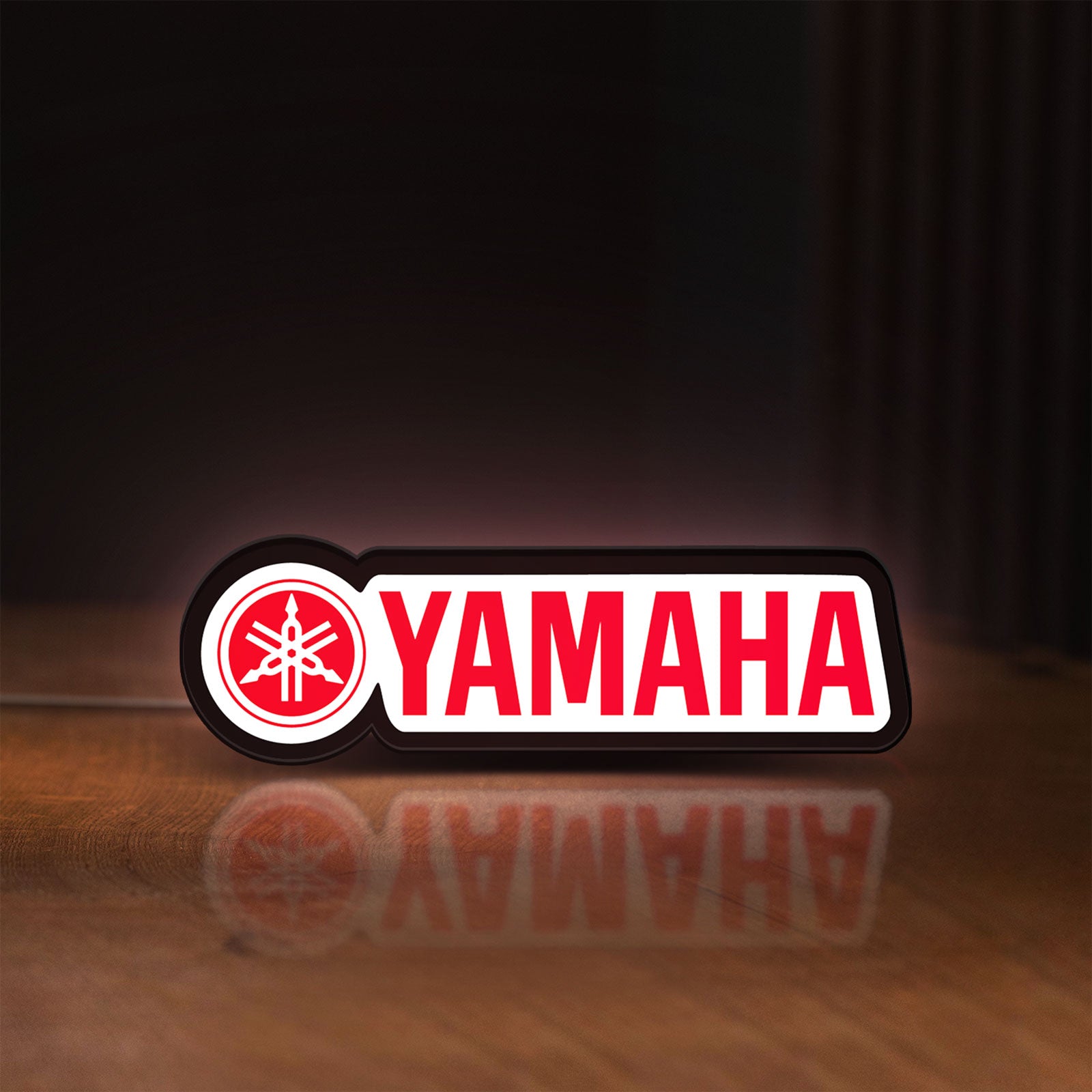Front view of Yamaha LED lightbox sign glowing on a wooden desk