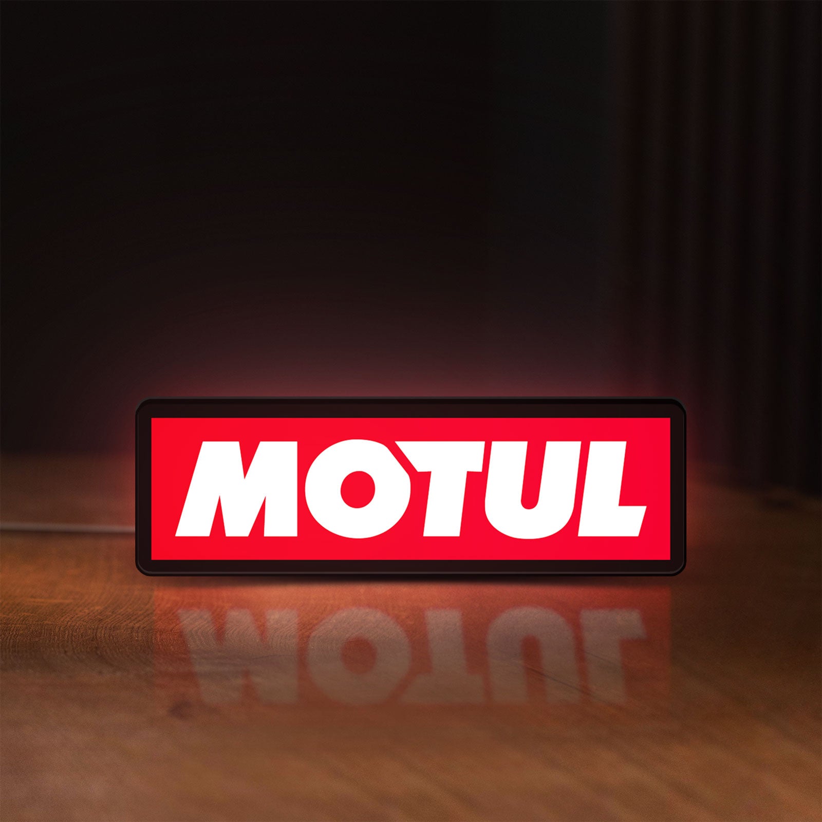 Front view of Motul LED lightbox sign glowing on a wooden desk