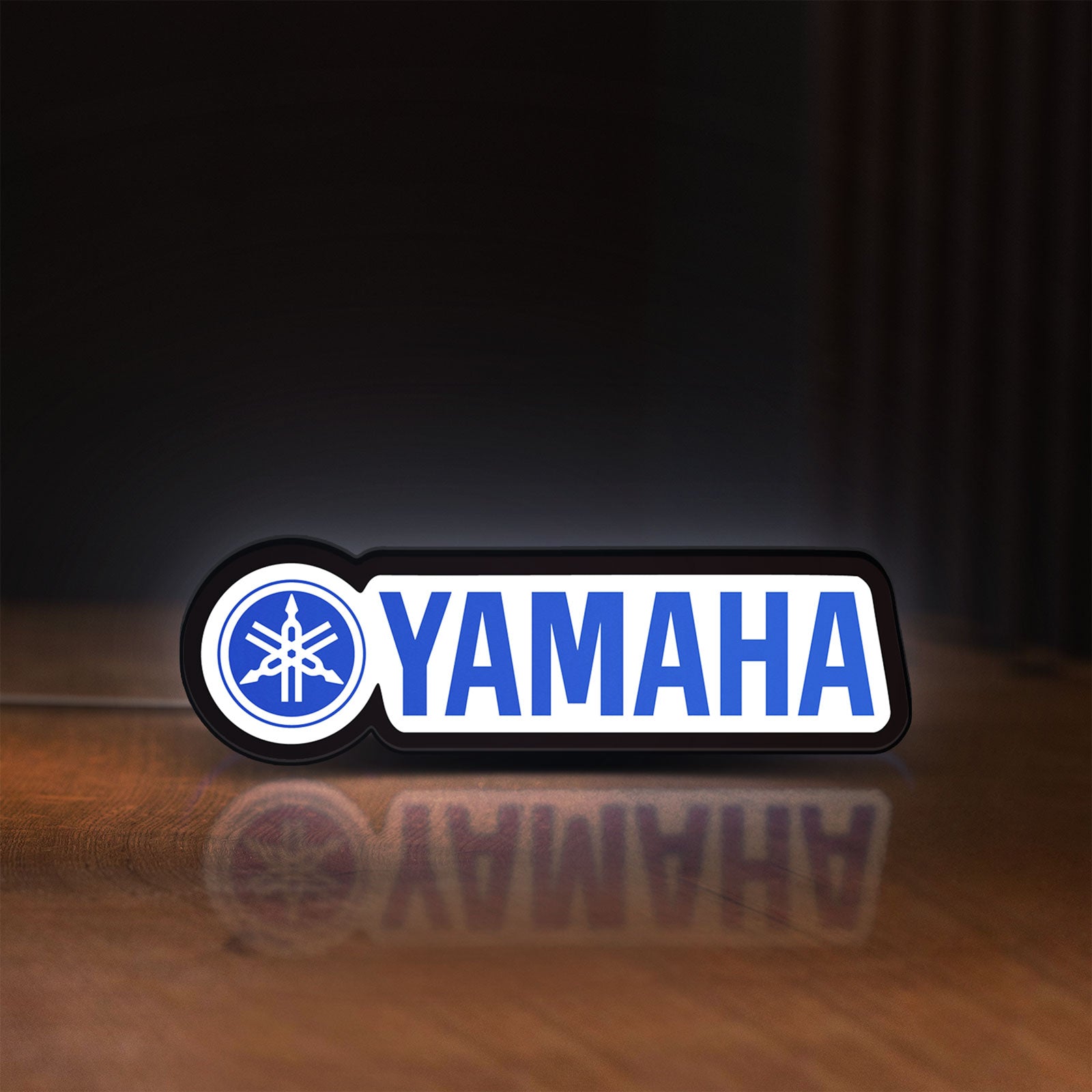 Front view of Yamaha LED lightbox sign glowing on a wooden desk