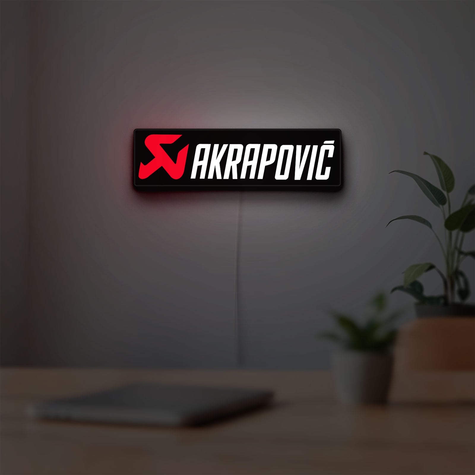 Akrapovic LED lightbox hanging on a room wall with soft red light