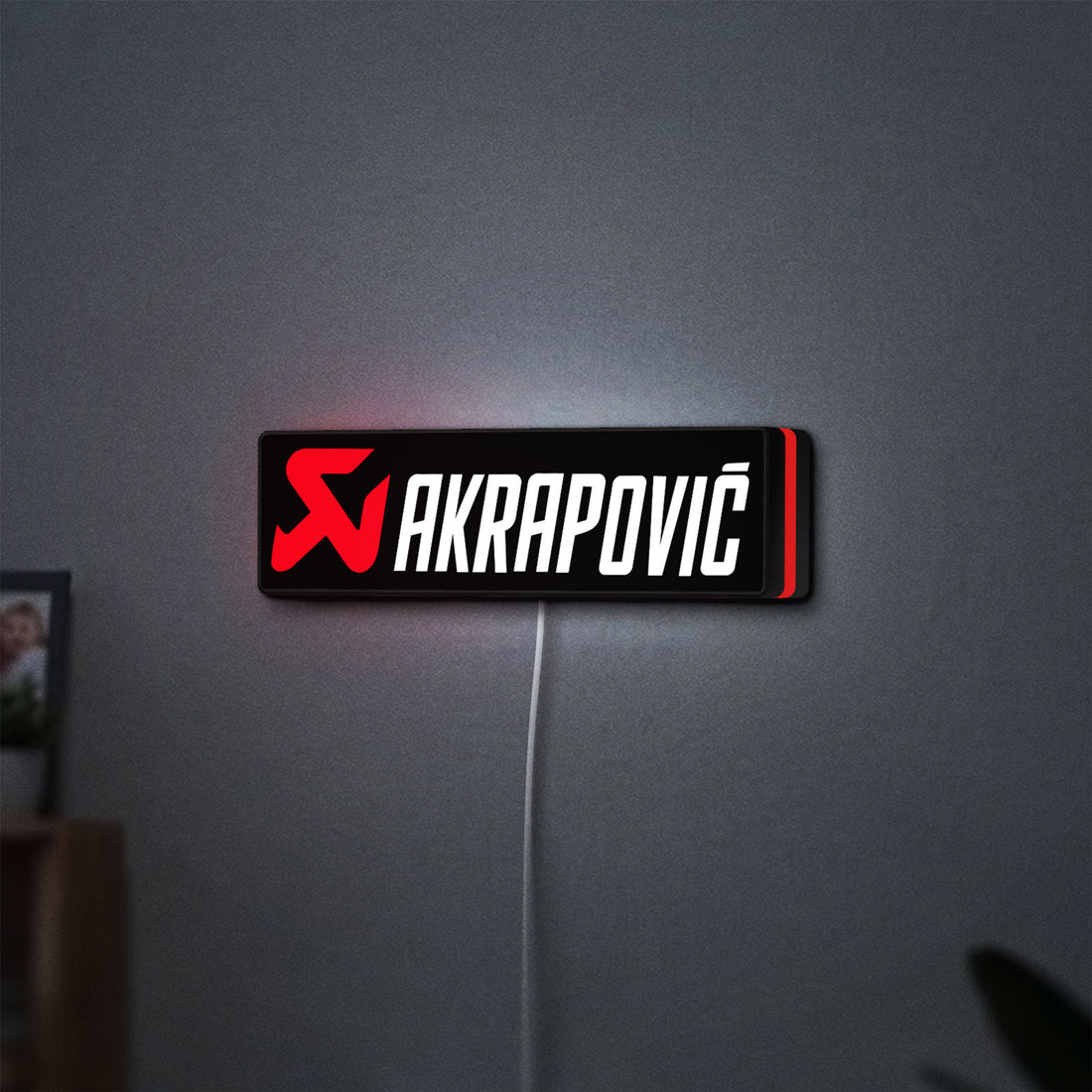 Akrapovic LED lightbox hanging on a wall with red glow