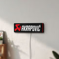 Unlit Akrapovic LED lightbox mounted on a wall in daylight