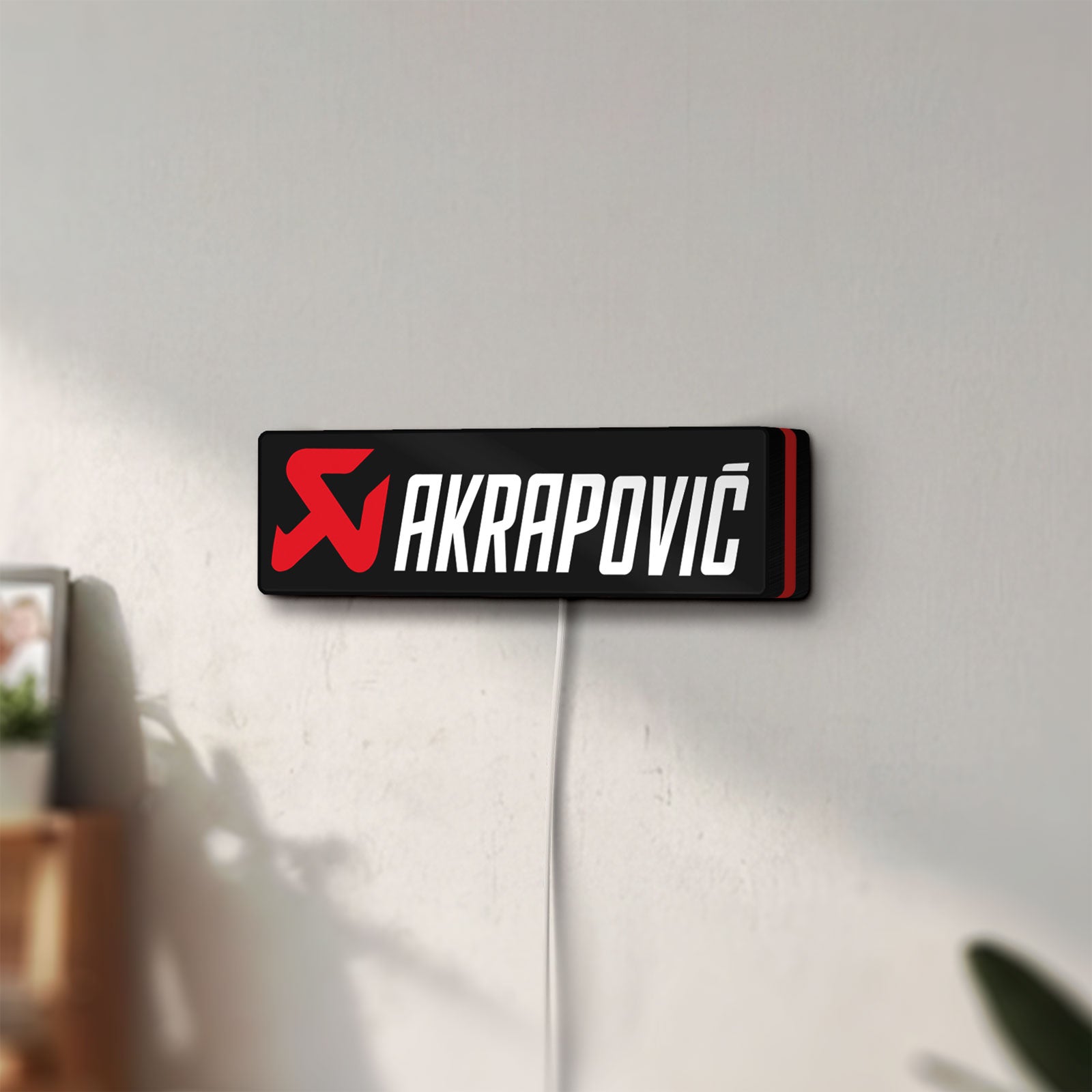 Unlit Akrapovic LED lightbox mounted on a wall in daylight