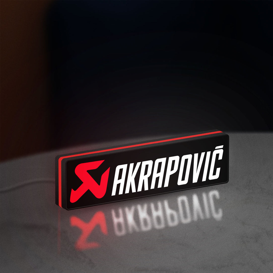 Akrapovic LED lightbox hanging on a wall with red glow