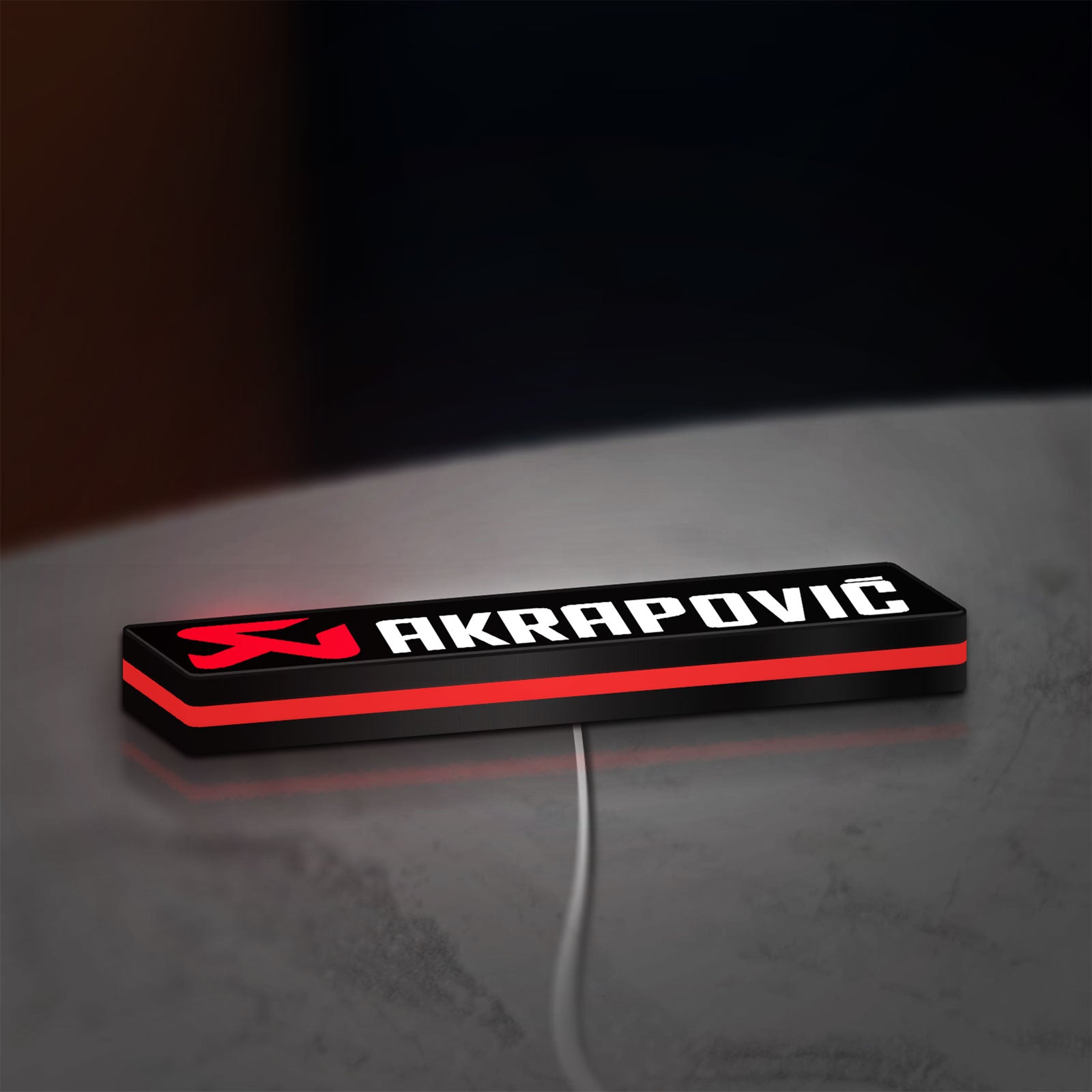 Akrapovic LED lightbox lying flat on a desk with red glow