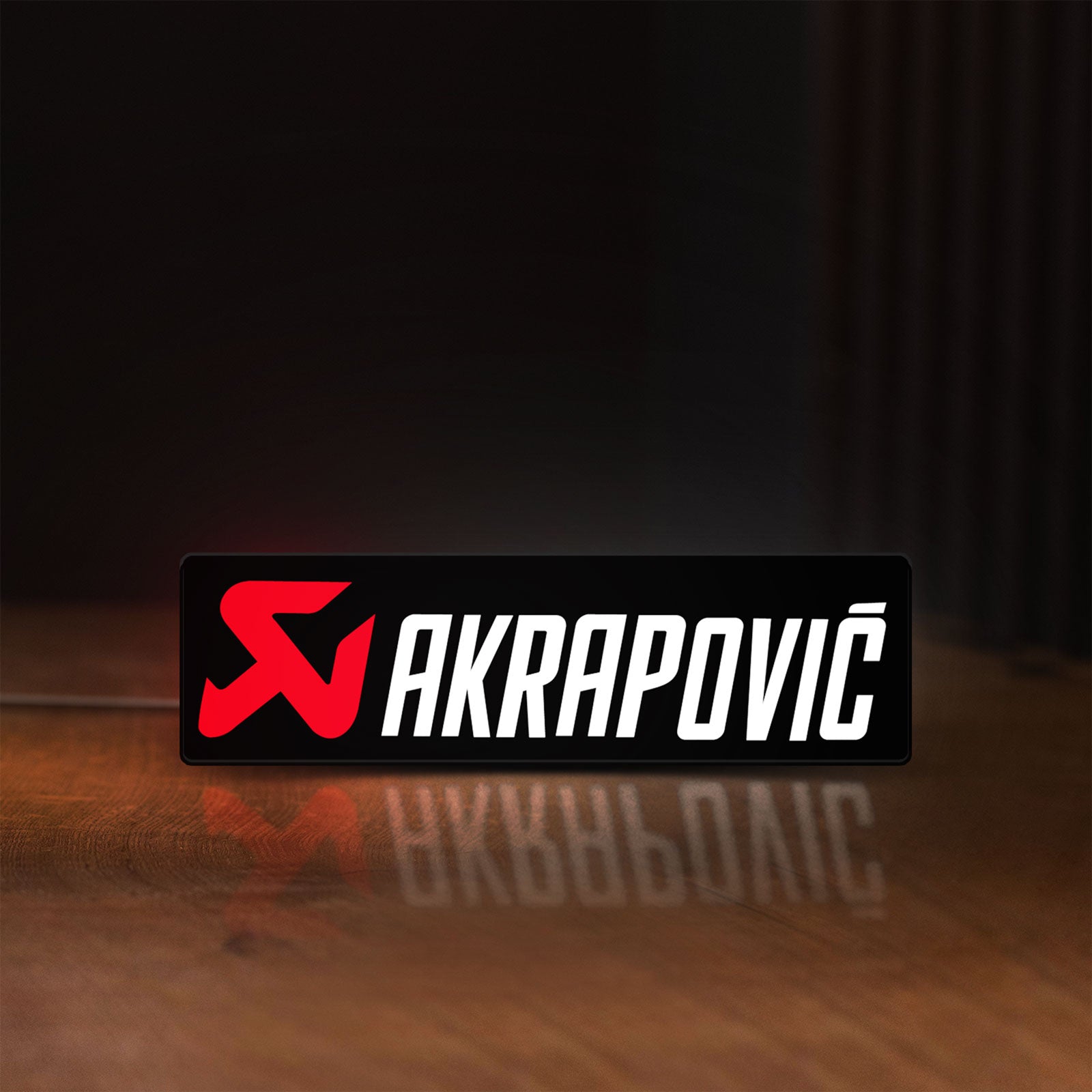 Front view of Akrapovic LED lightbox sign glowing on a wooden desk