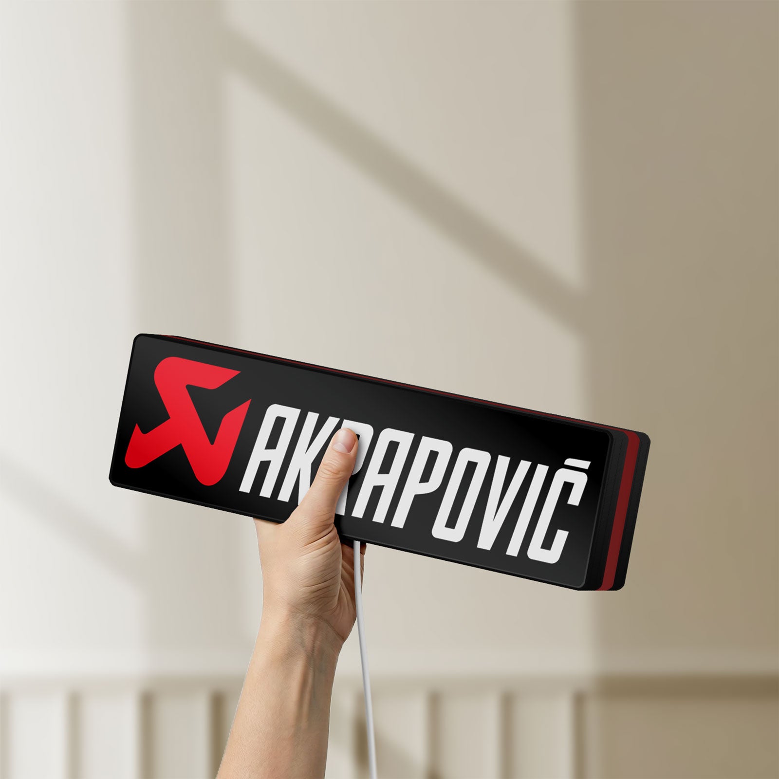 Unlit Akrapovic LED lightbox held by hand to show size and details
