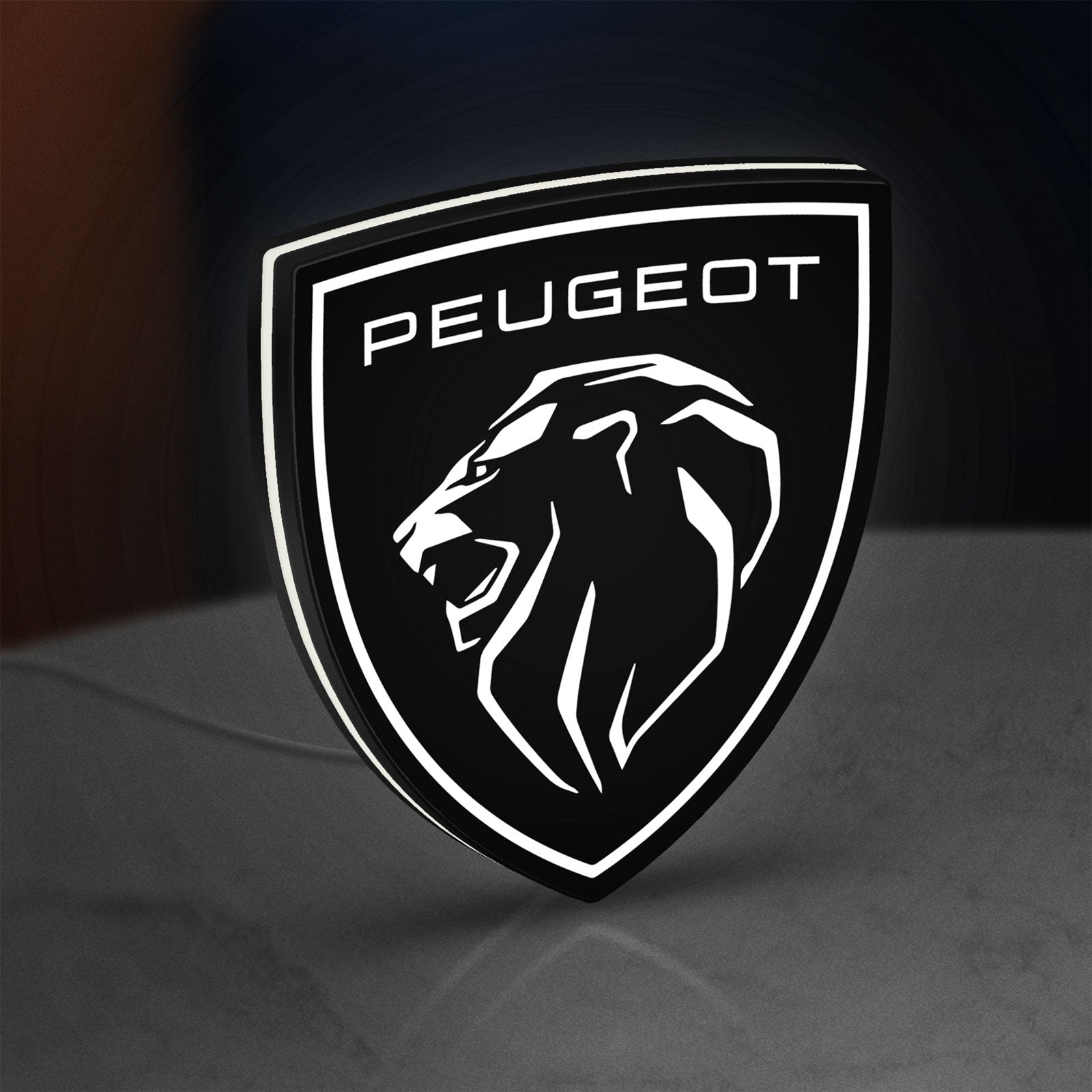 Peugeot Lion Head LED lightbox standing on a desk from an angled side view with white glow