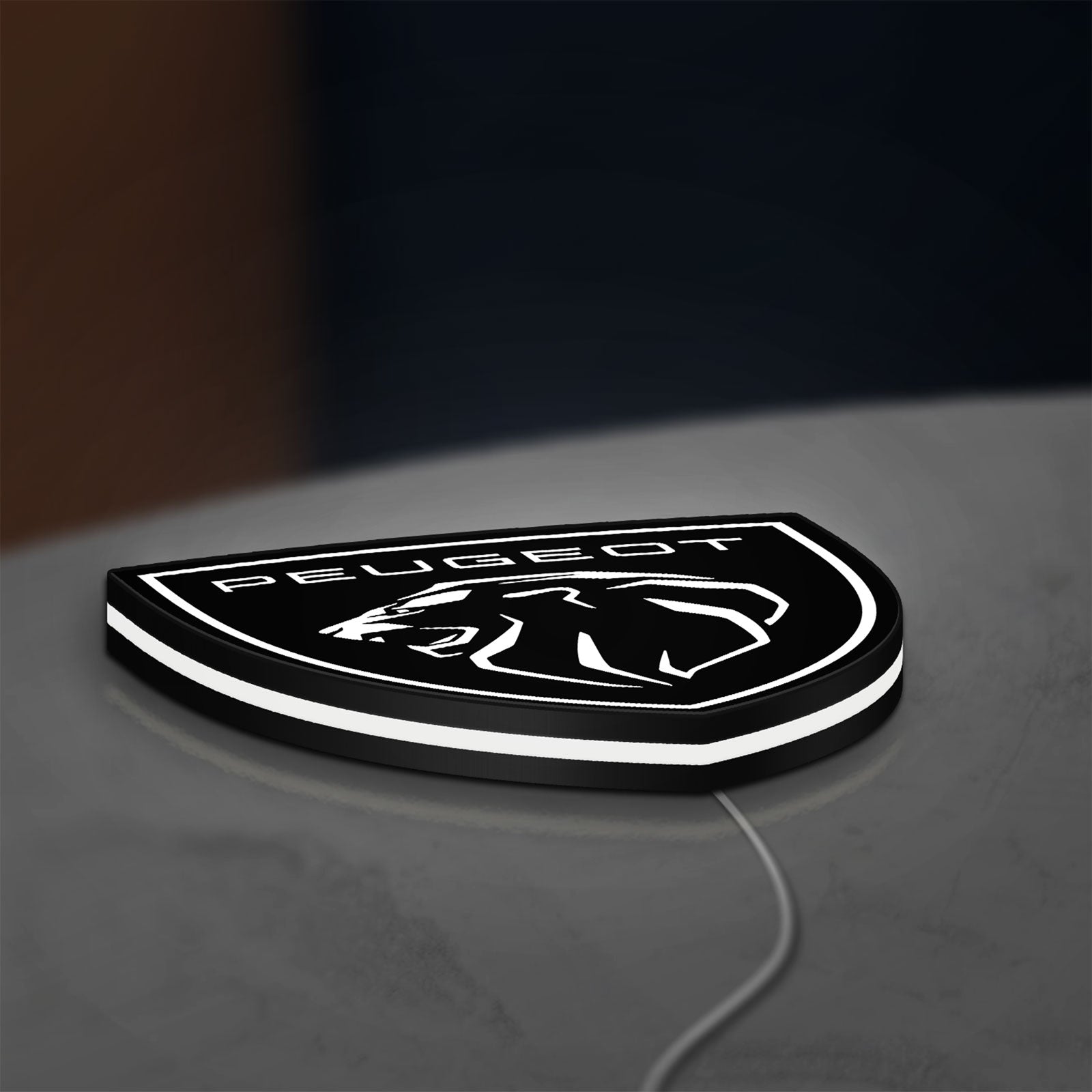 Peugeot Lion Head LED lightbox lying flat on a desk with white glow