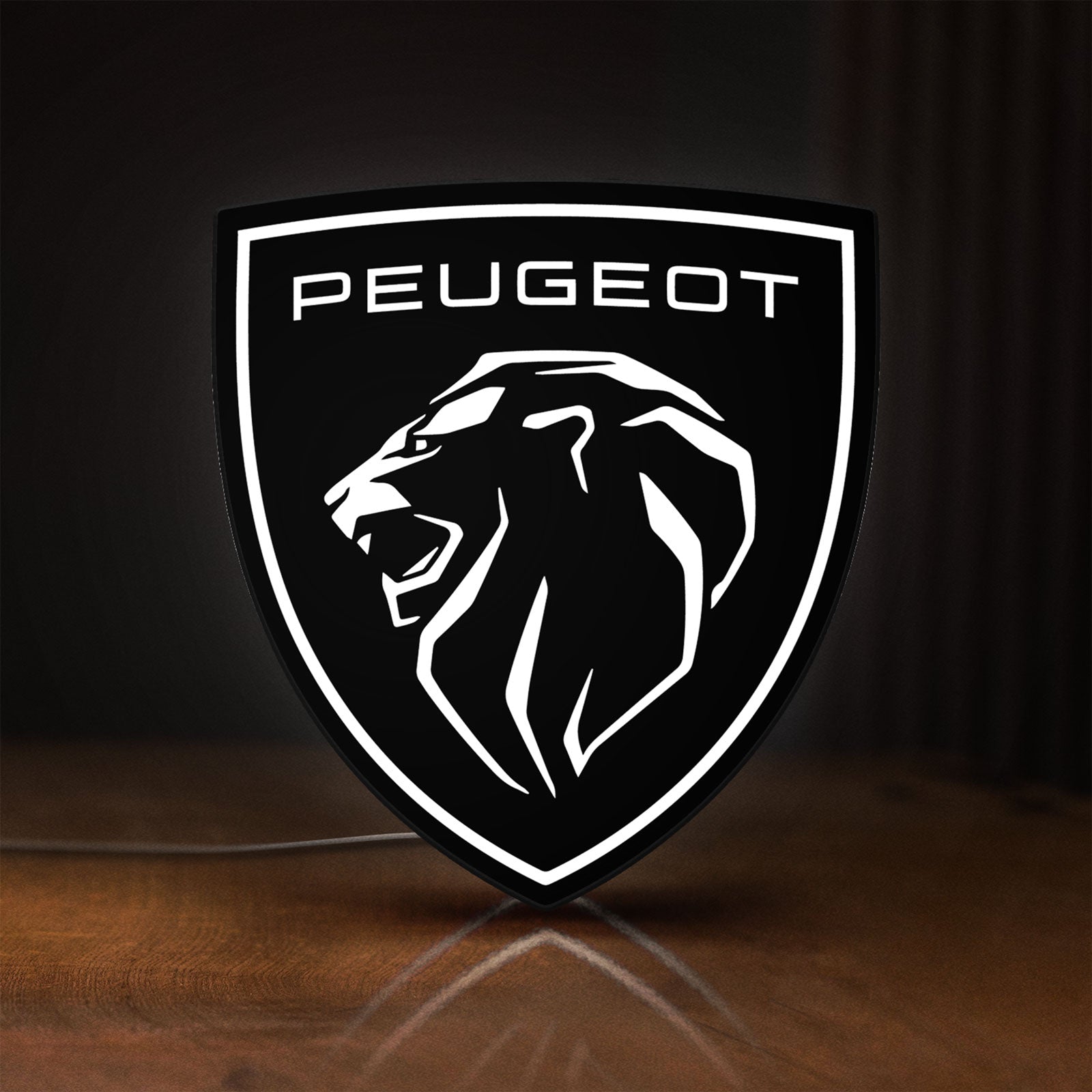 Front view of Peugeot Lion Head LED lightbox sign glowing on a wooden desk