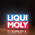 Front view of Liqui Moly LED lightbox sign glowing on a wooden desk