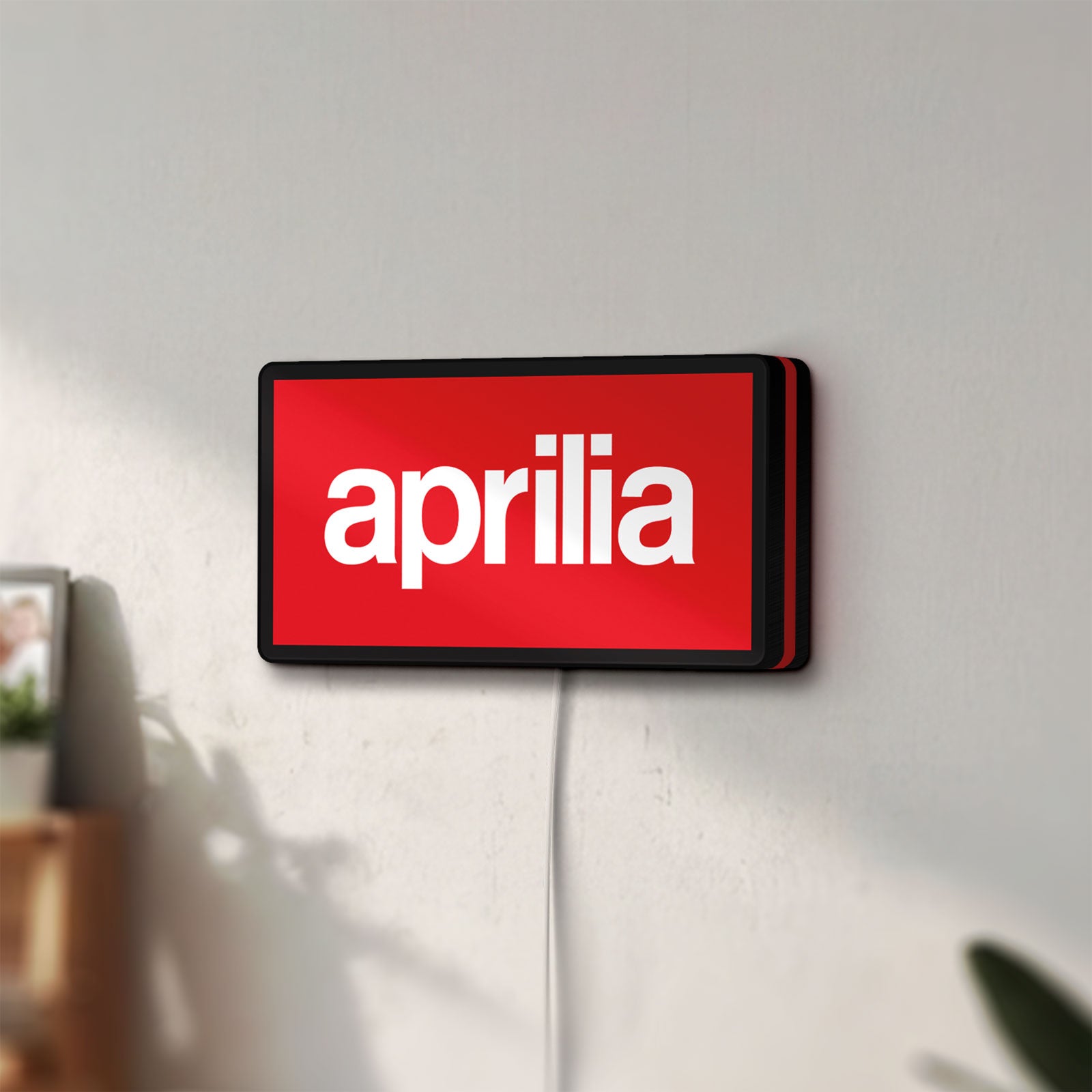 Unlit Aprilia LED lightbox mounted on a wall in daylight