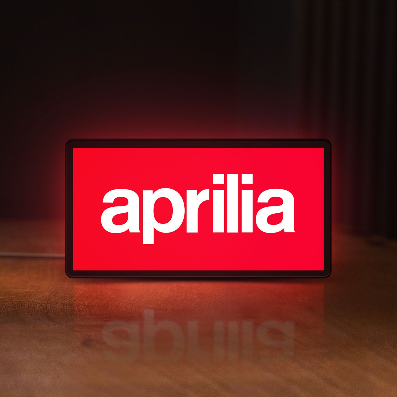 Front view of Aprilia LED lightbox sign glowing on a wooden desk