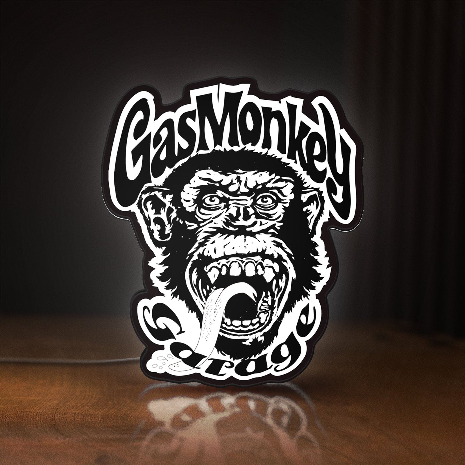 Front view of Gas Monkey Garage LED lightbox sign glowing on a wooden desk