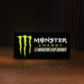 Front view of Monster Energy NASCAR Cup Series LED lightbox sign glowing on a wooden desk