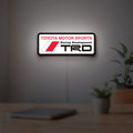 TRD LED lightbox hanging on a room wall with soft white light