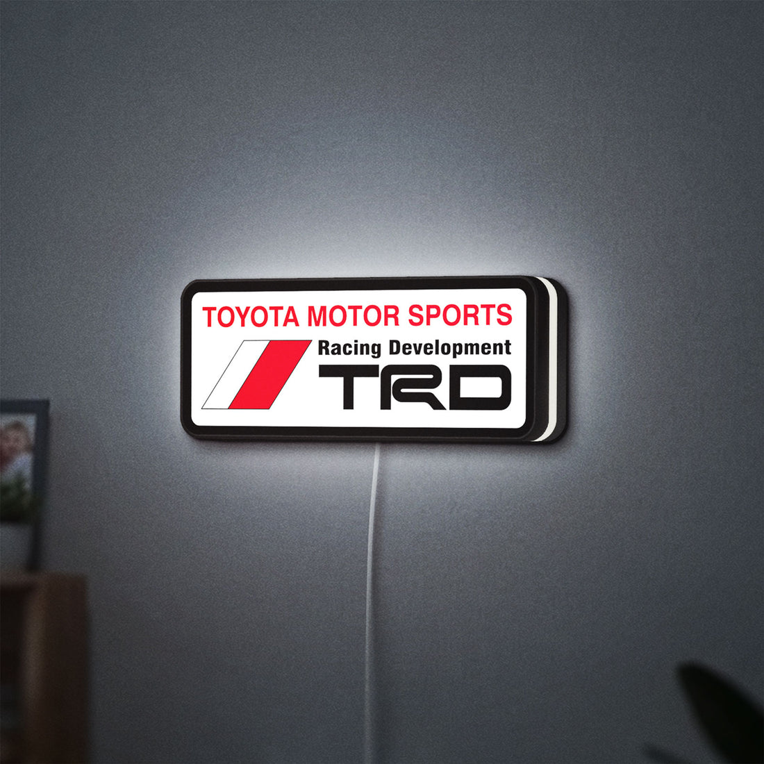 TRD LED lightbox hanging on a wall with white glow