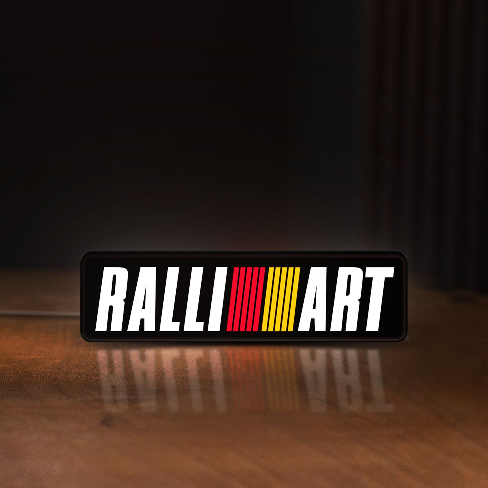 Front view of Ralliart LED lightbox sign glowing on a wooden desk