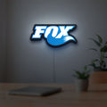 Fox Racing Shox LED lightbox hanging on a room wall with soft blue light