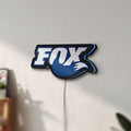 Unlit Fox Racing Shox LED lightbox mounted on a wall in daylight