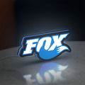 Fox Racing Shox LED lightbox standing on a desk from an angled side view with blue glow