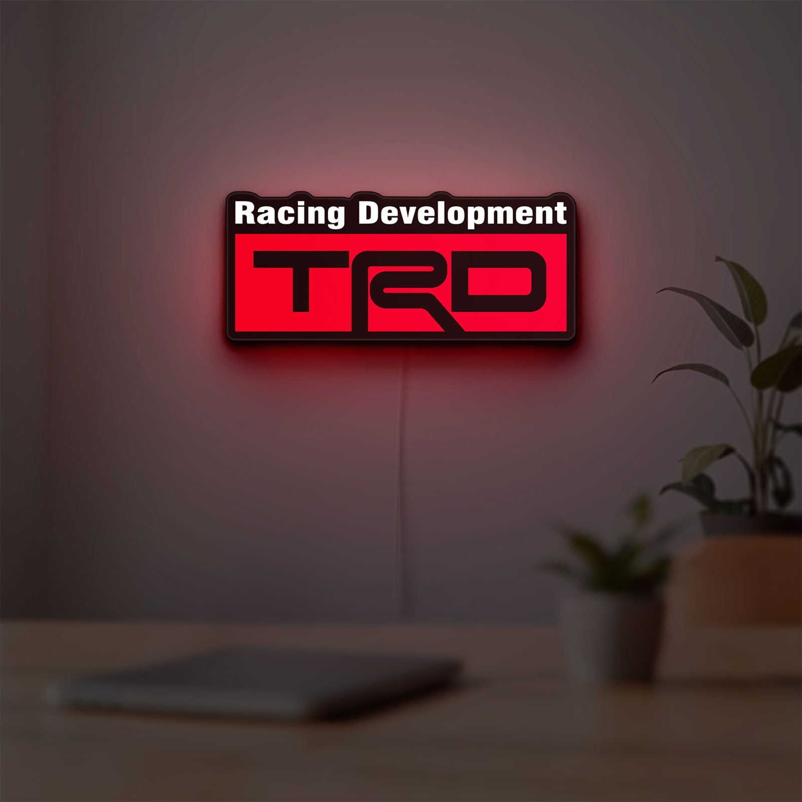 TRD Racing Development LED lightbox hanging on a room wall with soft red light
