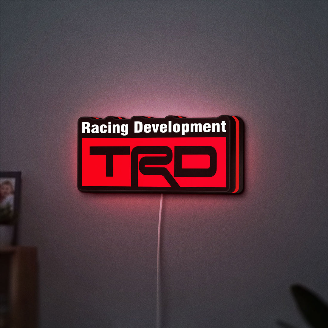 TRD Racing Development LED lightbox hanging on a wall with red glow