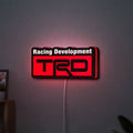 TRD Racing Development LED lightbox hanging on a wall with red glow