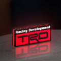 TRD Racing Development LED lightbox standing on a desk from an angled side view with red glow