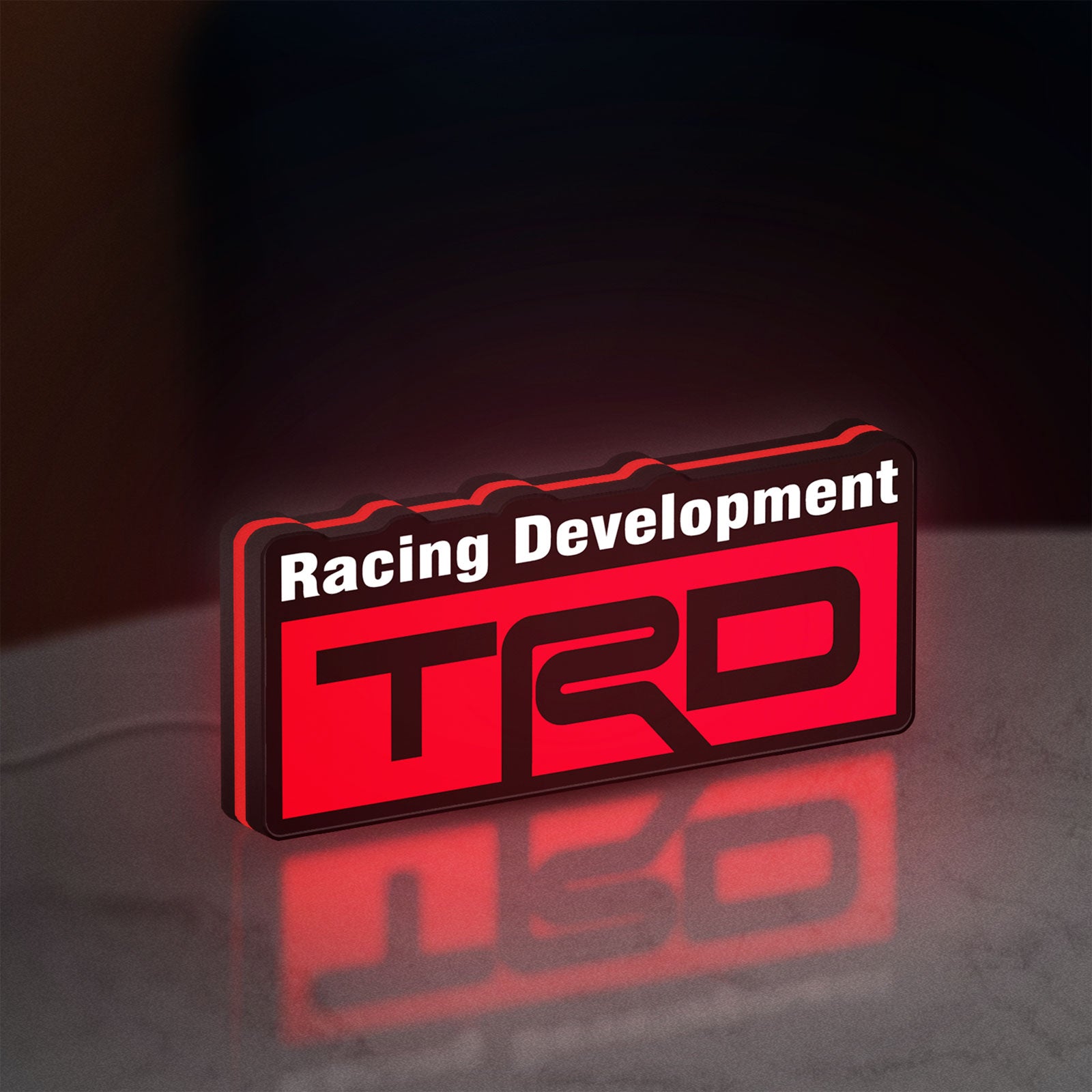 TRD Racing Development LED lightbox standing on a desk from an angled side view with red glow