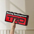 Unlit TRD Racing Development LED lightbox held by hand to show size and details