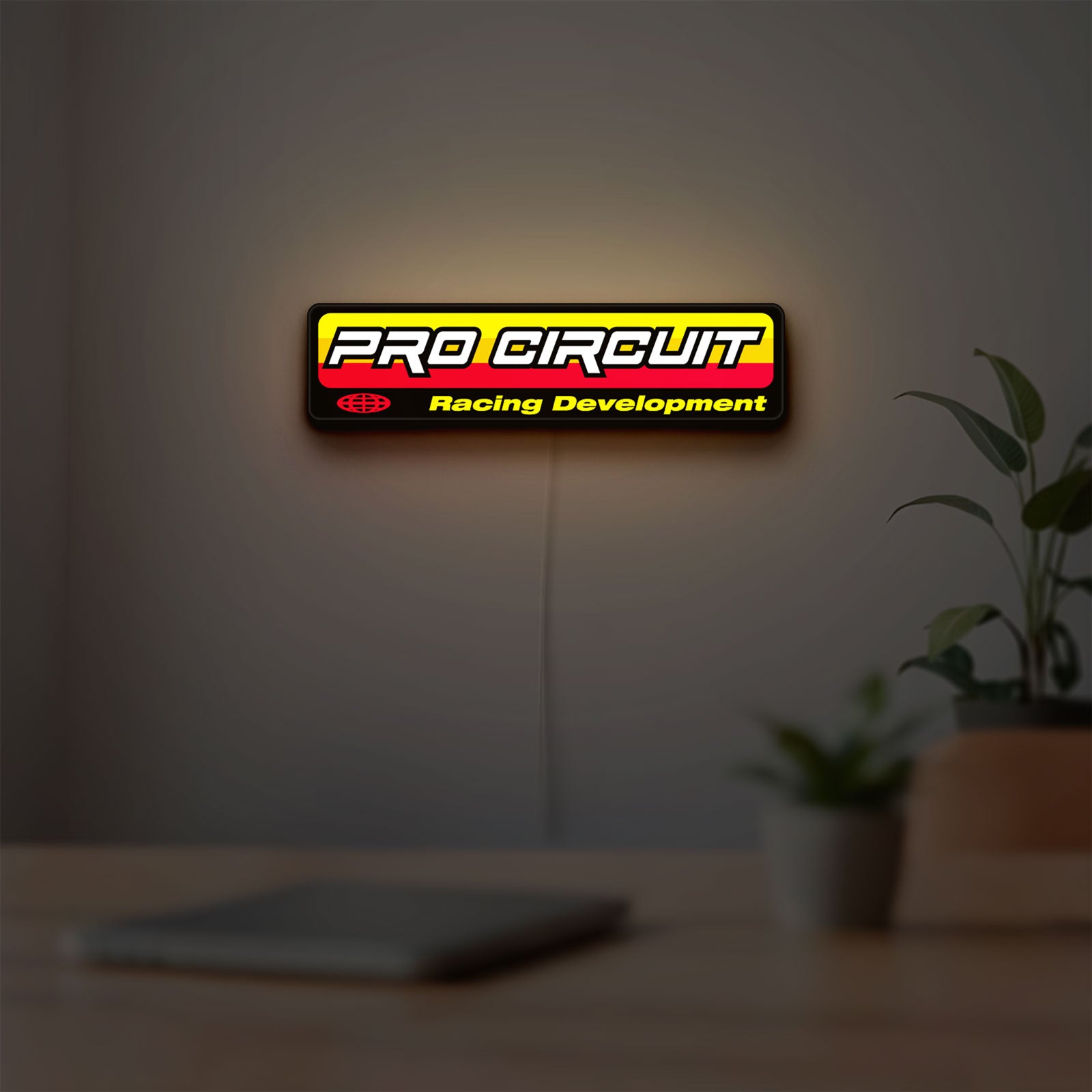 Pro Circuit Racing Development LED lightbox hanging on a room wall with soft yellow light