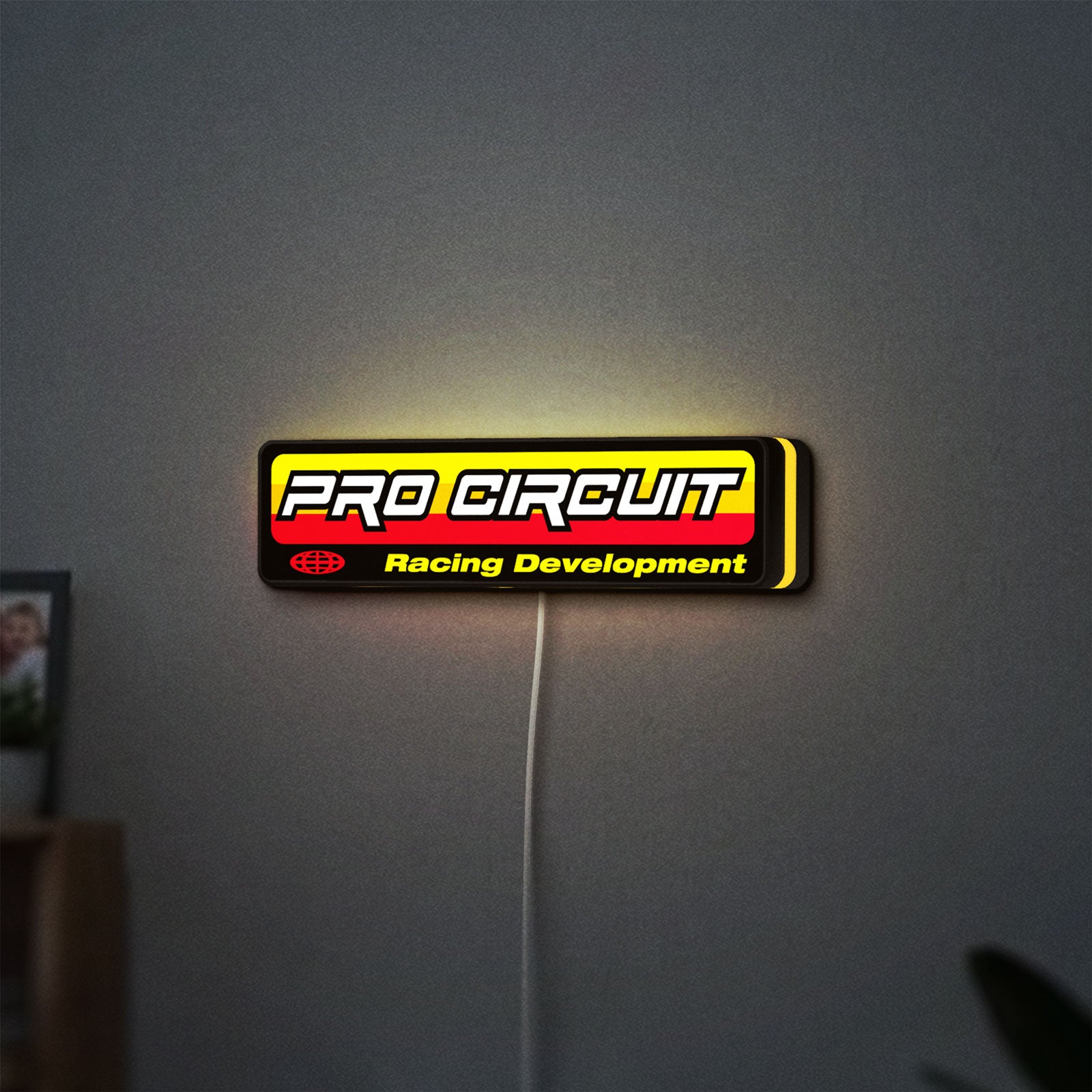 Pro Circuit Racing Development LED lightbox hanging on a wall with yellow glow