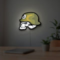 Metal Mulisha Skull LED lightbox hanging on a room wall with soft green light